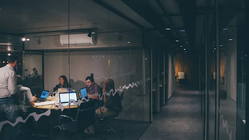 Staff working at a table in a glass-walled office meeting room